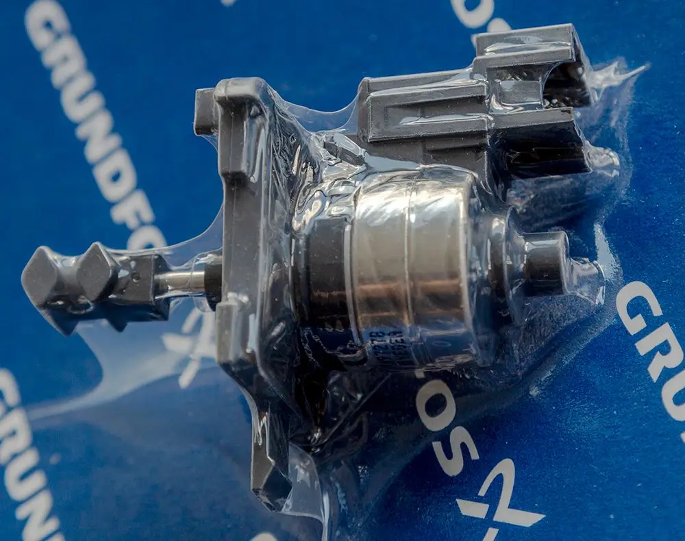 Daikin Schrittmotor in transparenter Verpackung, montiert auf blauem Hintergrund mit Logo. Sichtbare Anschlüsse an der Oberseite und ein metallischer Zylinder im Zentrum.